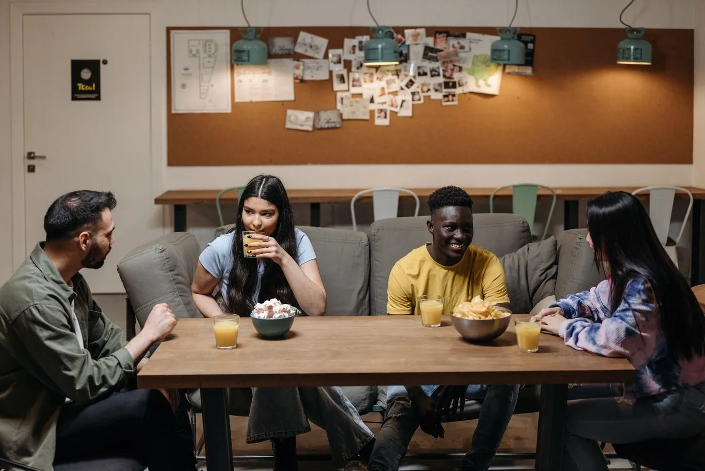 A group of friends sitting around a table, smiling and talking together.